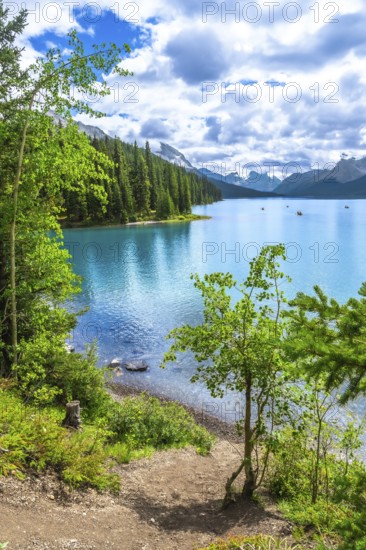Canoes are paddling on a beautiful turquoise lake surrounded by lush green trees and mountains in