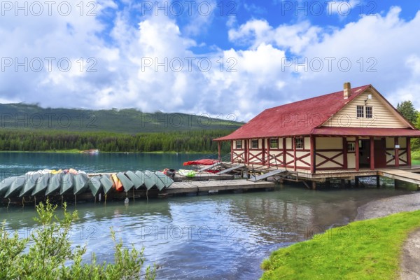 Colorful canoes and kayaks resting on a wooden dock in front of a boathouse on the beautiful