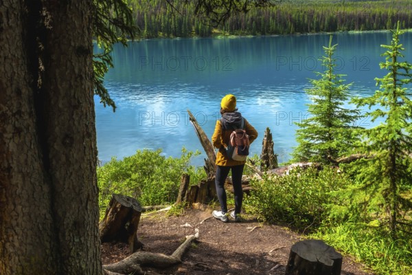 Female hiker admiring the stunning turquoise waters of maligne lake, surrounded by lush forests in