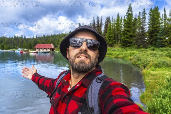 Happy tourist showing with open arms the beautiful maligne lake with the boathouse at jasper