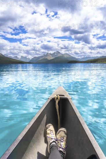 Tourist enjoys stunning view of turquoise water and mountain range while paddling canoe on maligne