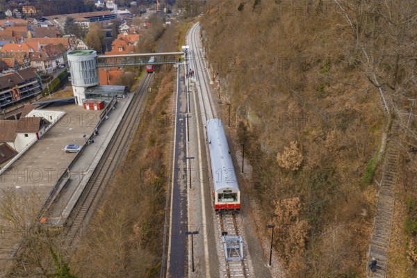 A station with a train that stops on the tracks while the autumn surroundings are visible, historic