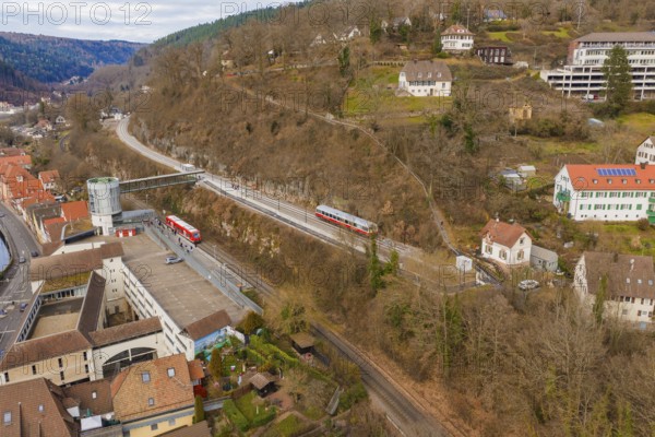 Zug crosses an urban landscape with hilly terrain and houses under a cloudy sky, historic event,