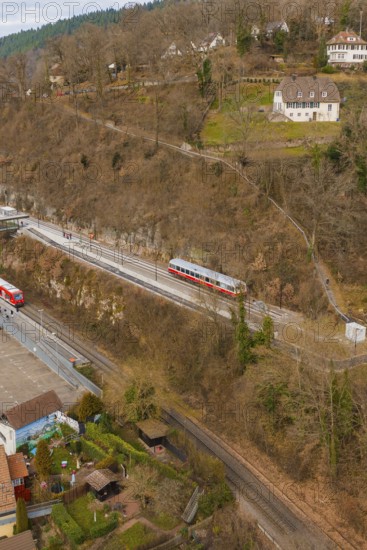 Train travels through hilly terrain with buildings and trees in a winter environment, historic