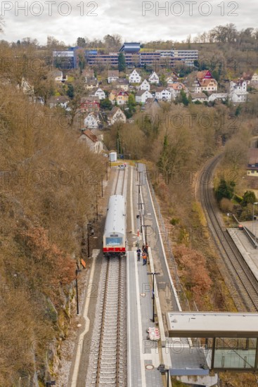 A train stops at a station on a hill with a view of a town with many buildings, historic event,