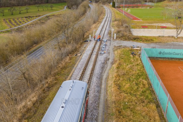 Aerial view of railway tracks next to a sports field with a passing train, historic event, first