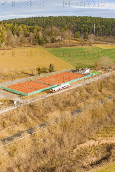 Land view of tennis courts next to a moving track, historic event, first test run with a passenger