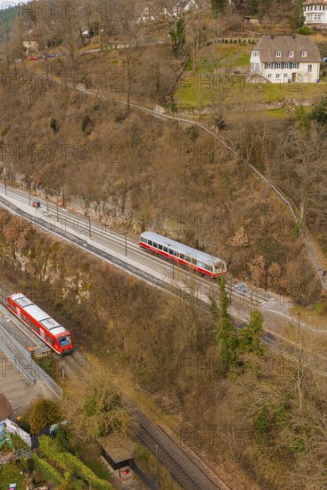 Train on tracks next to wooded hills with buildings in a wintry landscape, historic event, first