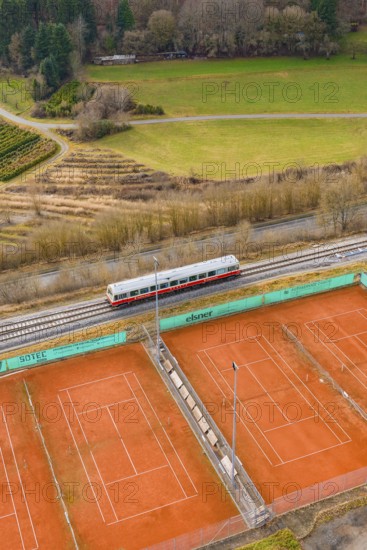 Landscape view with train next to tennis courts and meadows, historic event, first test run with