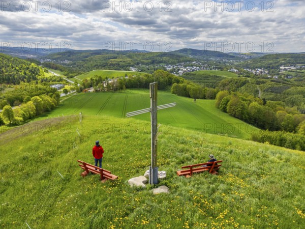 Two hikers under the Silberberg Pilgrim Cross with views over green landscapes, Bad Schlema, Ore