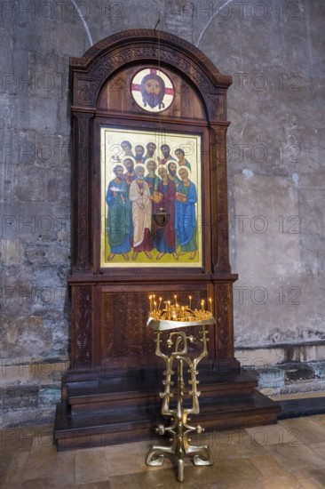 A wooden altar with icons of saints and glowing candles in a church, Svetitskhoveli Cathedral,