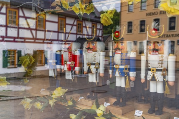 Window of a wooden nutcracker shop, reflecting a half-timbered house, health resort and toy village