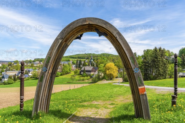 View through a wooden arch of residential buildings and landmarks of the historic mountain church,