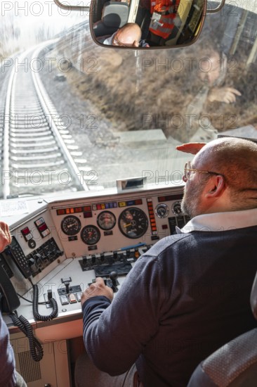 Train driver steers the train from a modern cockpit while traveling on rails, historic event, first