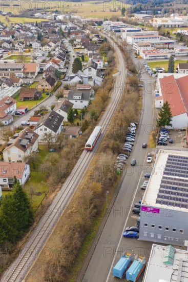 Suburb with a train, surrounded by roads, parked cars and residential buildings in a slightly
