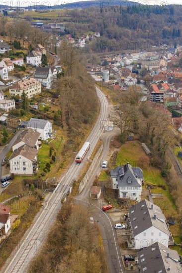 Train through suburban area with nearby houses and a wooded landscape, historic event, first test