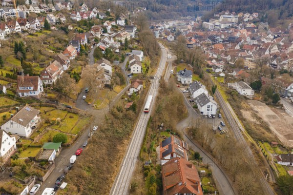 City with close-standing houses along a railway line through hilly, wooded landscape, historic