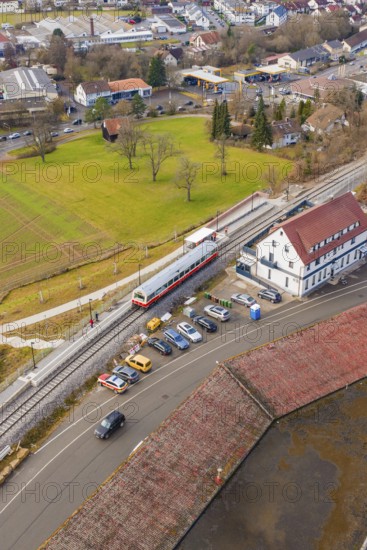 A train at a train station in an urban area with parked cars, historic event, first test run with a