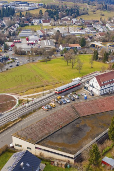 A train stops at a train station in a small town area with residential buildings, historic event,