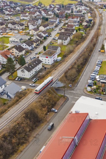 Train crossing a road junction in a residential and industrial area with red roofs, historic event,