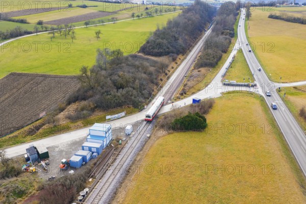 A rural scene with a train on rails, surrounded by fields and roads, historic event, first test run