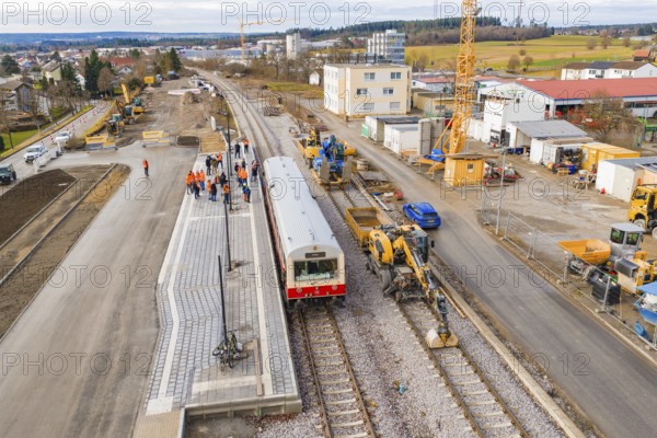 Train surrounded by workers and cranes at construction site, industrial buildings and vehicles in