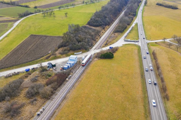 Train travels near a country road in a rural area with fields and vehicles, historic event, first
