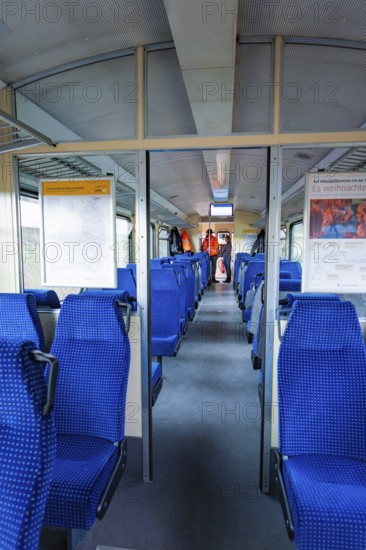 Interior of a train with blue seats and windows through which daylight enters, historic event,