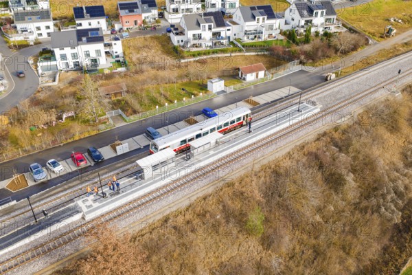 Small train stops at a railway stop within a residential development, historic event, first test