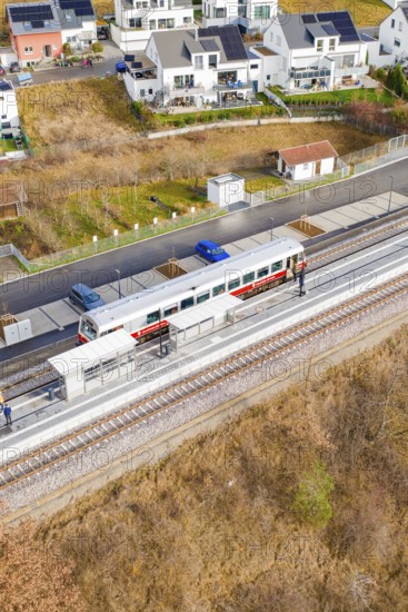 Train on the platform, surrounded by residential buildings and parked cars, historic event, first