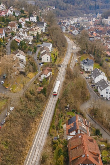 A train travels through a hilly urban landscape with numerous buildings, historical event, first