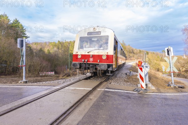 Train on a rail crossing, surrounded by trees, under a cloudy sky, historic event, first test run