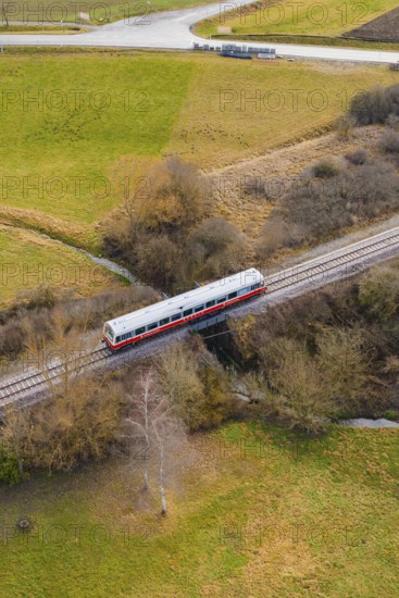 A train crosses a bridge over a river, surrounded by trees in a rural landscape, historic event,