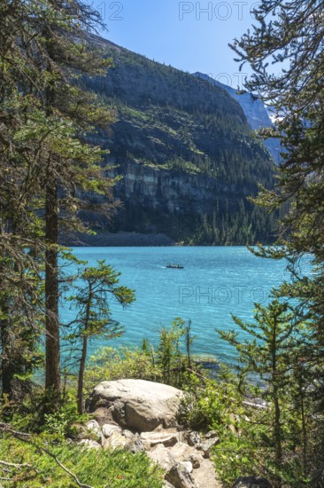 Tourists are canoeing on the turquoise, glacier fed moraine lake with the scenic valley of the ten