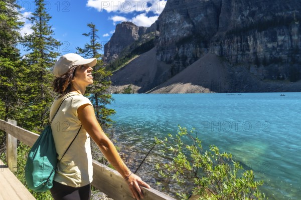 Female tourist admiring the turquoise waters of moraine lake, with the stunning valley of the ten