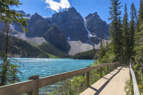 Moraine lake in banff national park features turquoise water, a wooden boardwalk, snow capped