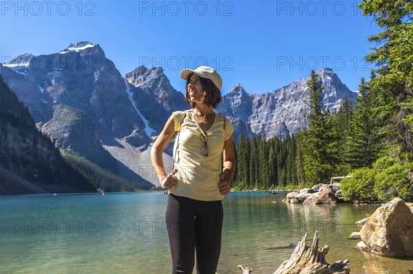 Female tourist standing at the shore of turquoise moraine lake enjoying the breathtaking view of