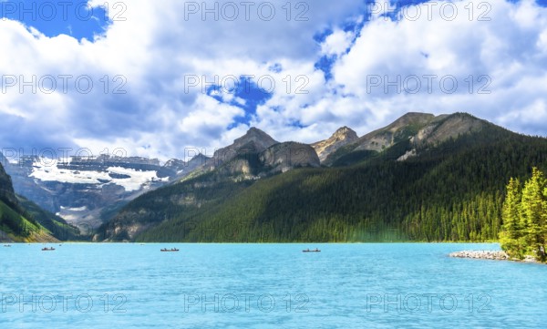 Canoeing on the turquoise waters of lake louise, tourists enjoy a breathtaking summer landscape