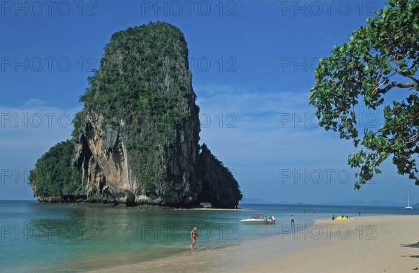 Rocks in the sea, tree, boat and people on Pranang Cave beach, two years in front of the tsunami,