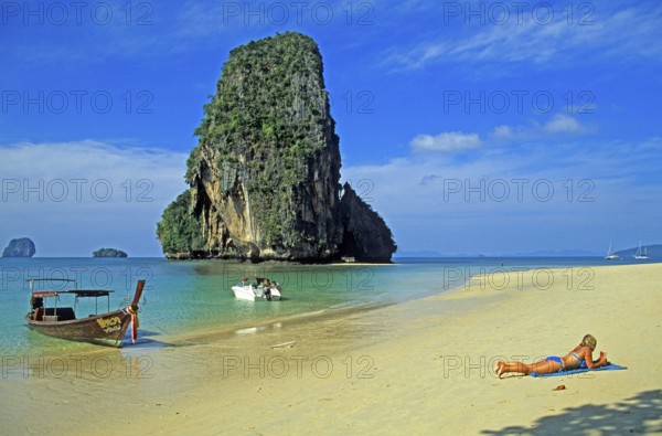 Rocks in the sea, people and longtail boat on Pranang Cave beach, two years in front of the