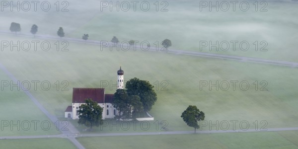 St. Coloman pilgrimage church in front of sunrise in autumn fog, Königswinkel, Ostallgäu, Allgäu,