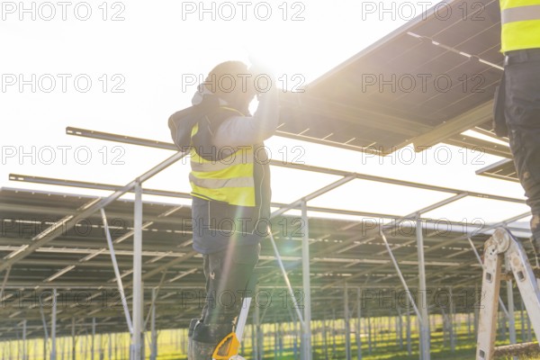 Person mounts solar panel on frame, bright sun in background, Energiewende, construction of PV open