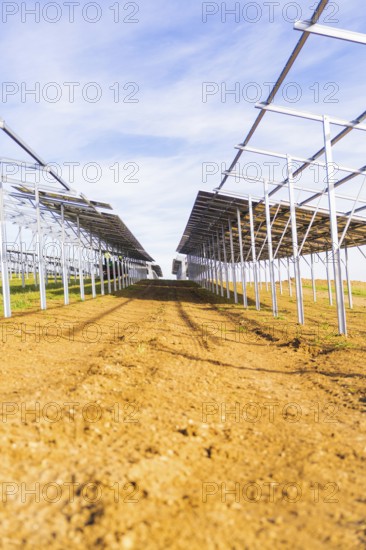 Straight rows of metal structures under blue sky, Energiewende, construction of PV open space,