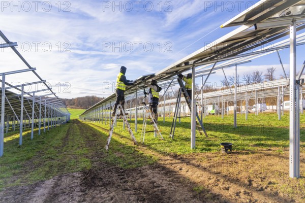 Workers install solar panels on a sunny day, Energiewende, construction of PV open space,