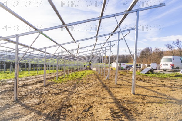 Unfinished solar system in open area with vehicles and building materials, energy transition,