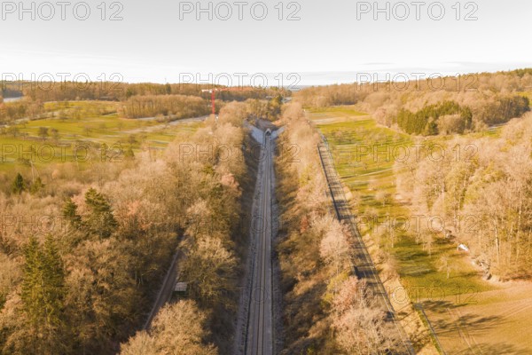 Train route from above, flanked by autumnal forests, running through nature, construction of the