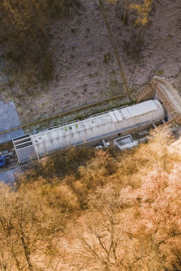 View of a train in a tunnel entrance amidst a frosty forest landscape, construction of the Hermann