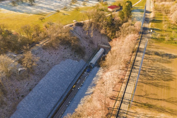 Drone view of a railway line through an autumn landscape with meadows and forests, construction of