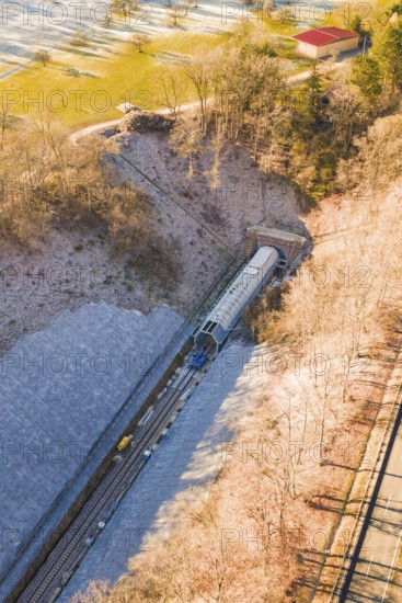 A Train Emerges from a Tunnel Surrounded by Forested Hills in a Wintry Setting, Construction of the