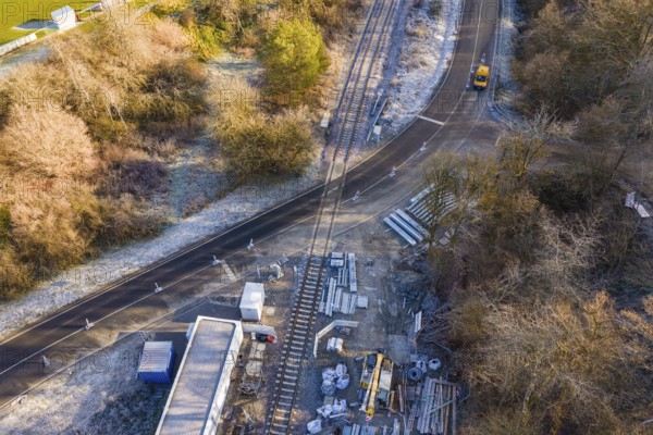 Construction site on a railway line with building materials and a moving vehicle, construction of